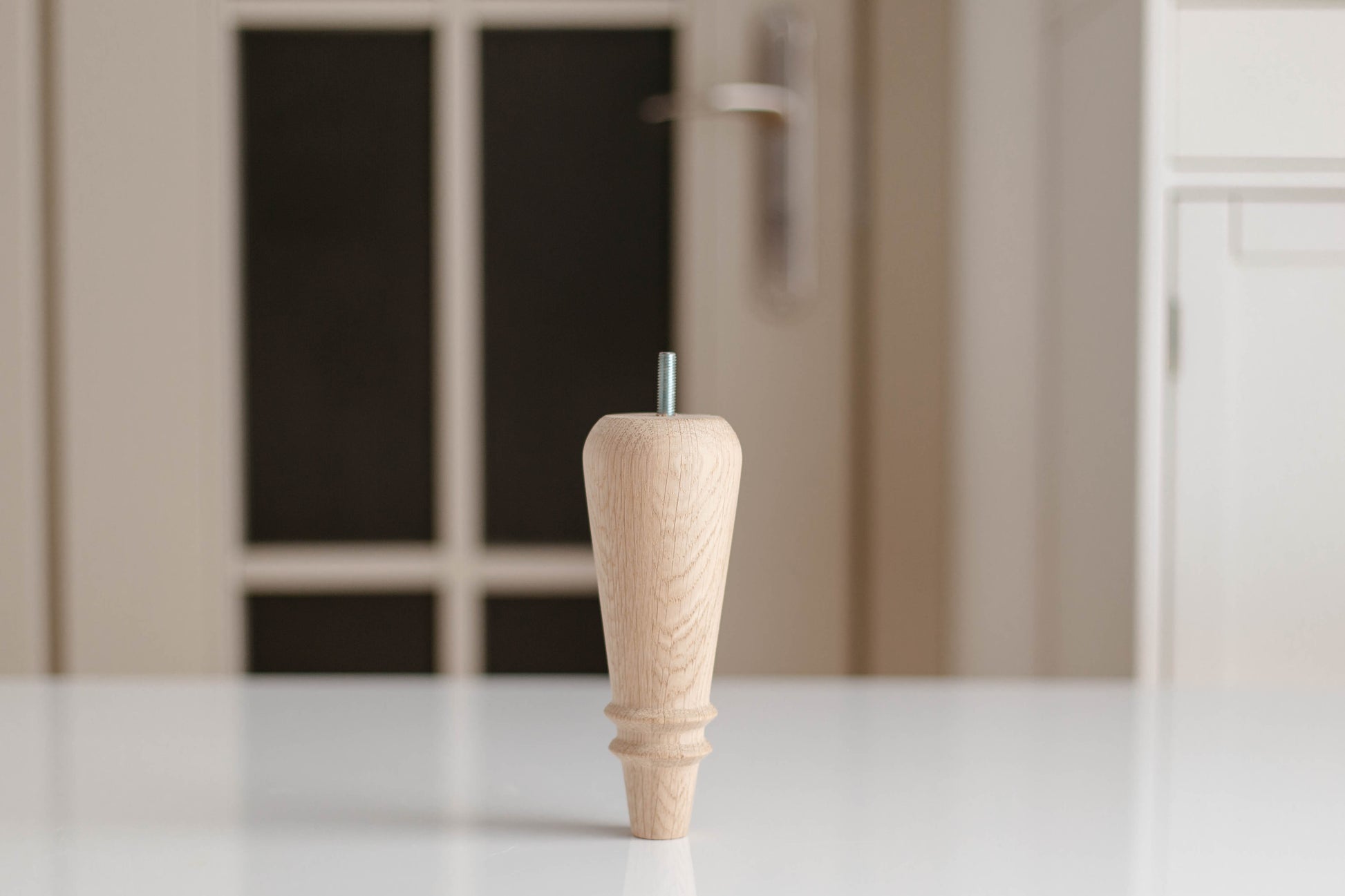 Wooden cabinet knob on a white surface with a blurred background