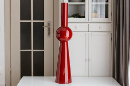 Red vase on a white surface with a neutral background